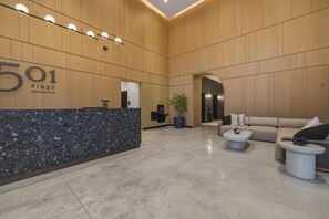 A modern reception area with a marble counter, a reception desk, a seating area with a sofa and two coffee tables, and a potted plant. - New Luxury Studio Downtown Miami Prime Location (Miami)