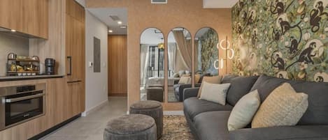 A modern living room with a grey sofa, ottomans, and a patterned rug.