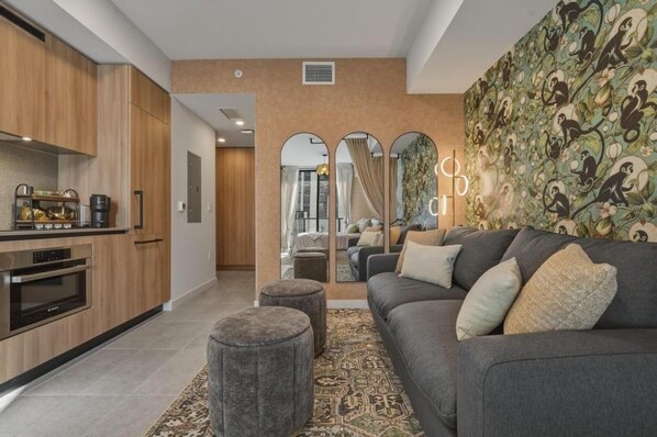 A modern living room with a grey sofa, ottomans, and a patterned rug. - New Luxury Studio Downtown Miami Prime Location (Miami)