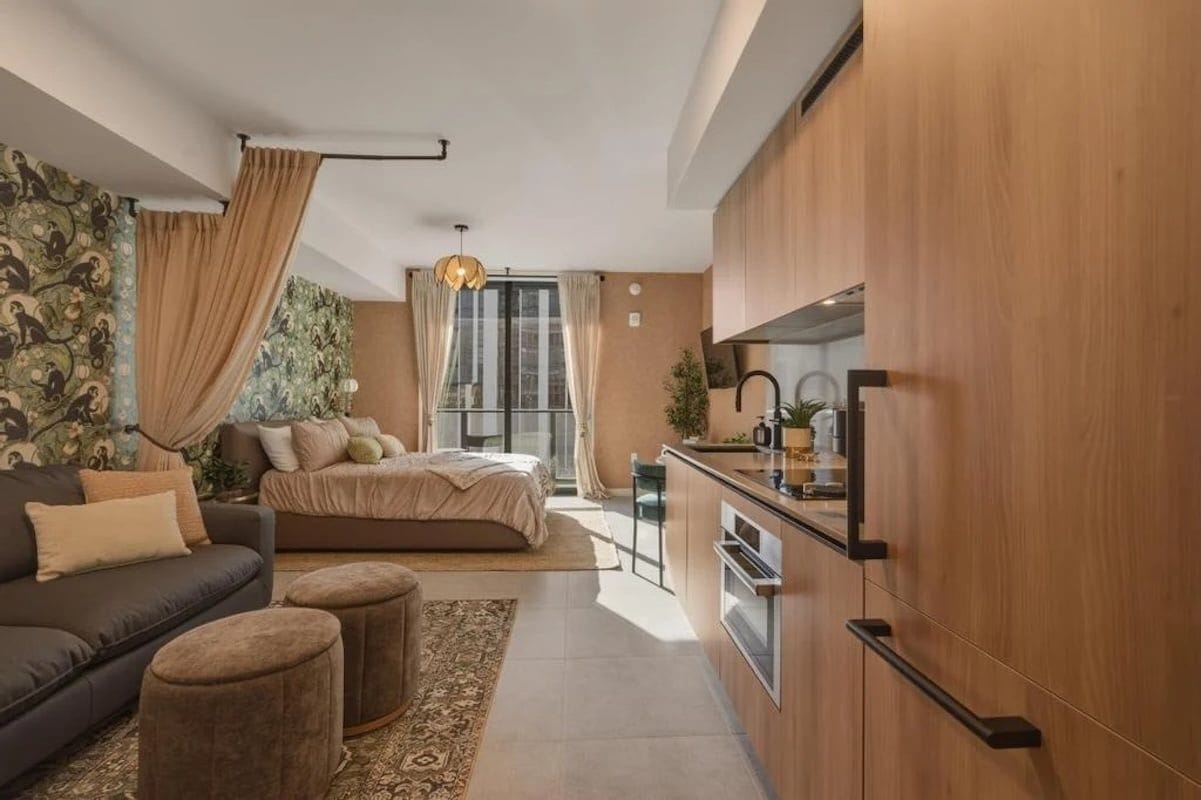 A modern apartment with a kitchenette, a sofa, a bed, and a dining area.