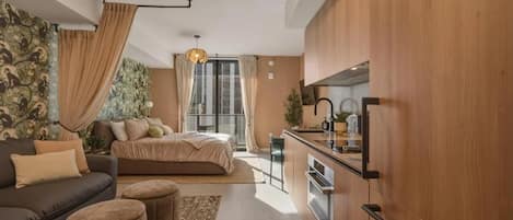 A modern apartment with a kitchenette, a sofa, a bed, and a dining area.