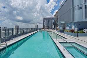 A rooftop swimming pool with a city view, a building with a sign indicating rental prices, and a clear sky. - New Luxury Studio Downtown Miami Prime Location (Miami)