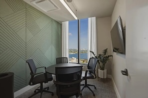 A conference room with a large table, four chairs, a potted plant, and a TV on the wall. - New Luxury Studio Downtown Miami Prime Location (Miami)