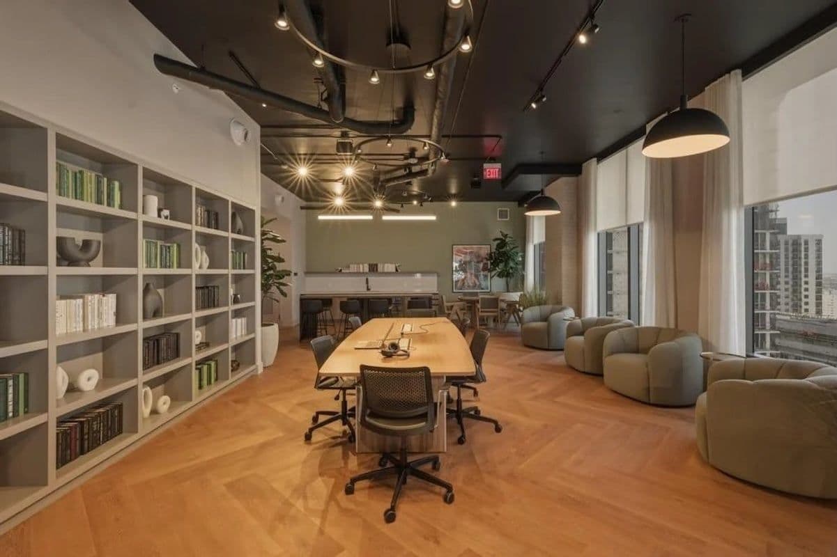 A modern office space with a long table, comfortable seating, and bookshelves.