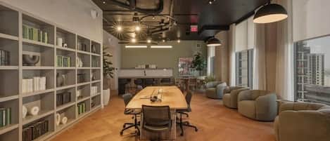 A modern office space with a long table, comfortable seating, and bookshelves.