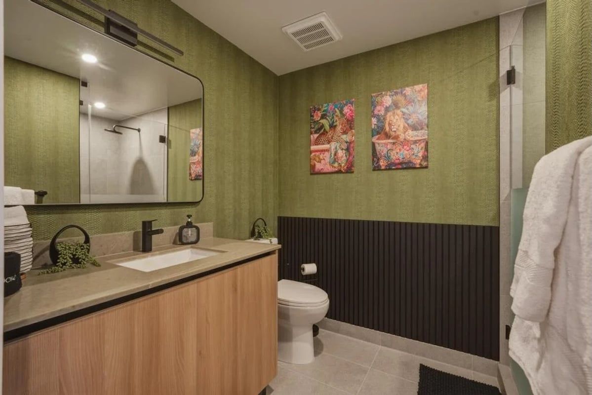 Un bagno con un mobile bagno in legno, un WC bianco e due quadri floreali appesi al muro.
