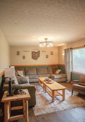 A cozy living room with a sofa, a wooden coffee table, and a lamp. - Heart of the Hocking Hills Lodge Newly renovated (Rockbridge)