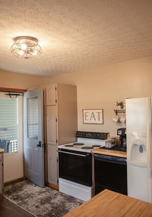 A compact kitchen with a stove, oven, refrigerator, and a sign that says 'EAT'.