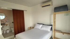Ein Schlafzimmer mit einem Bett, einem Holzschrank, einer Klimaanlage und einem Spiegel.