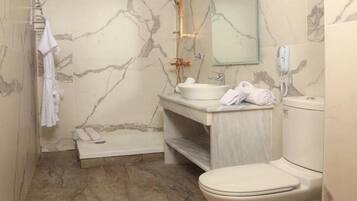 Un baño con pared de mármol, una bañera, un lavabo, un inodoro y un perchero para toallas.