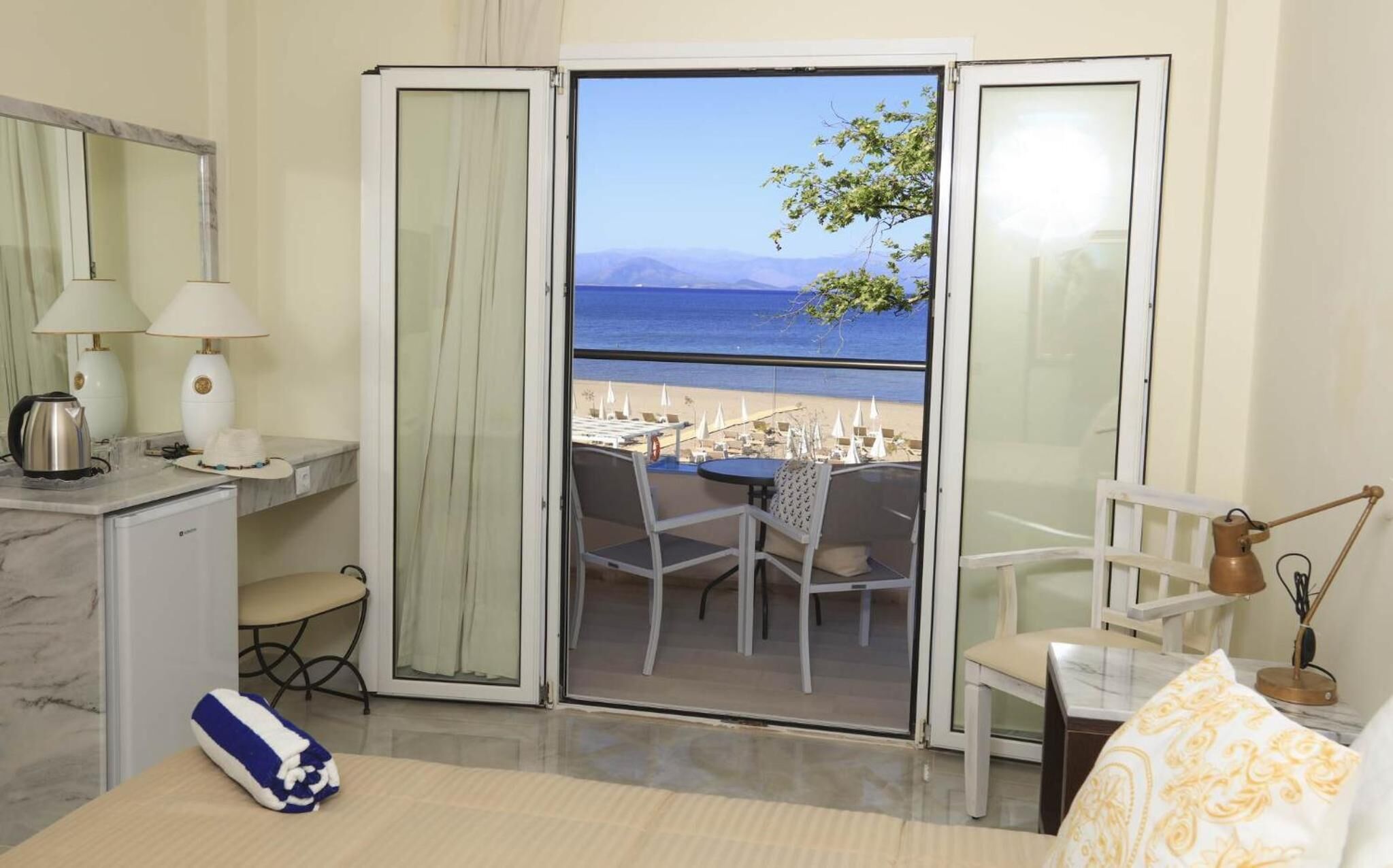 Ein Zimmer mit Balkon, Schreibtisch, Stuhl, Tisch und Bett.