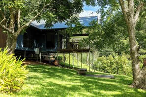 A modern house with a covered porch, surrounded by lush greenery and trees. - Under the Pecans | 2BR Retreat with Peaceful Scenic Views (Woombye)