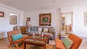 Una sala de estar con sofá, dos sillones, una mesa de centro y un espejo grande.
