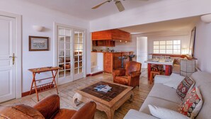 A spacious living room with a wooden coffee table, leather armchairs, a sofa, and a ceiling fan. - Appartement Le Bateau Tropézien - Welkeys (Saint-Tropez)
