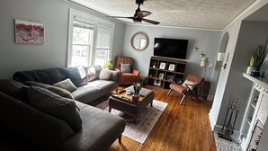 Ein Wohnzimmer mit Sofa, Hocker, Couchtisch und Deckenventilator.