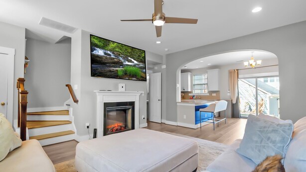 Ein modernes Wohnzimmer mit Kamin, einem darüber montierten Fernseher und einer Treppe, die zu einer weiteren Ebene führt.