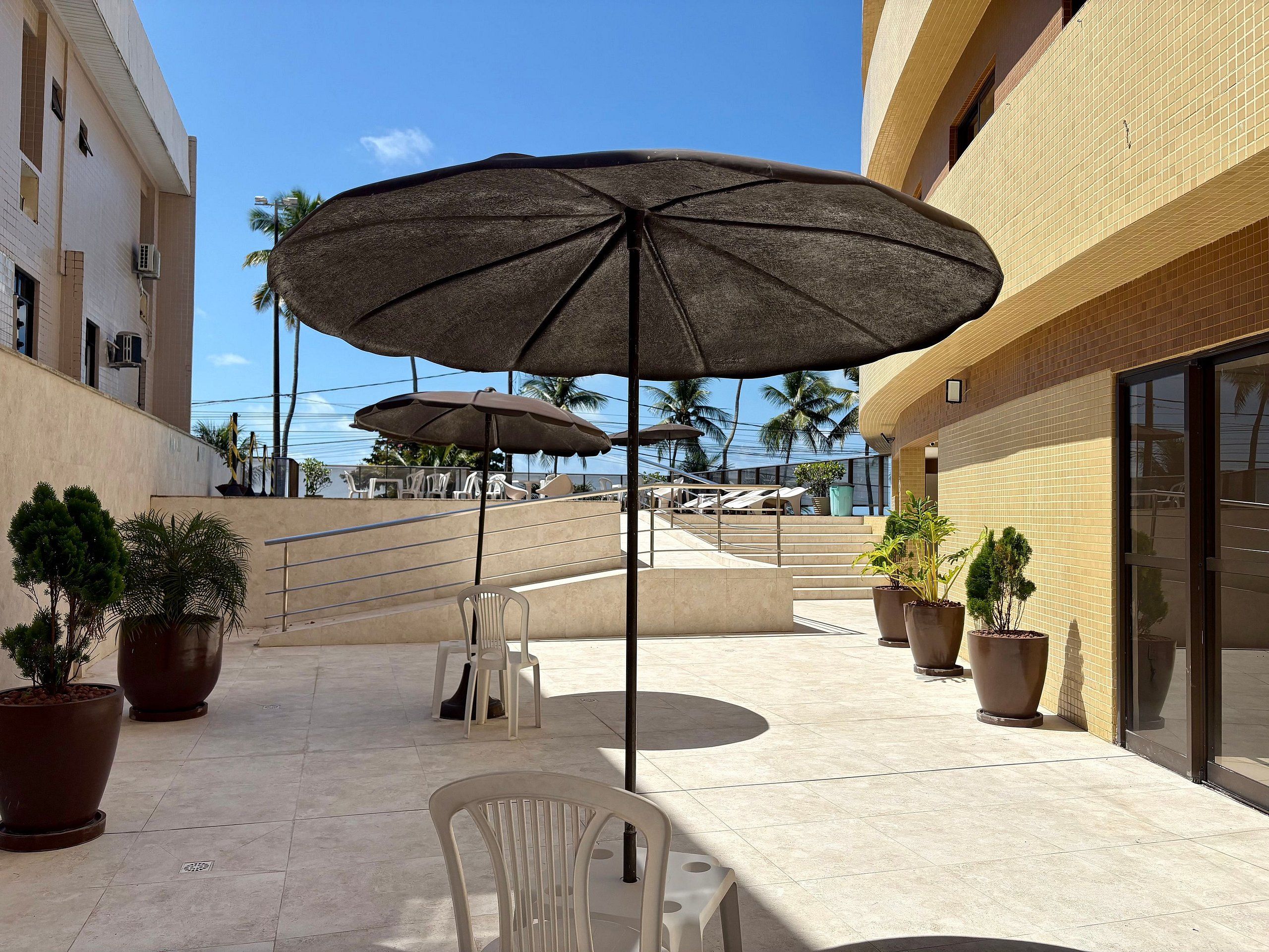 An outdoor seating area with umbrellas, potted plants, and a staircase leading to an upper level.