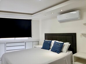 A bedroom with a bed, a window, a wall-mounted air conditioner, and a bedside table. - Boulevard Beira mar do Cabo Branco (João Pessoa)