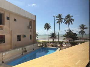 A swimming pool with a view of the beach and palm trees. - Boulevard Beira mar do Cabo Branco (João Pessoa)