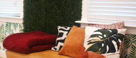A sofa with three pillows and a green wall.