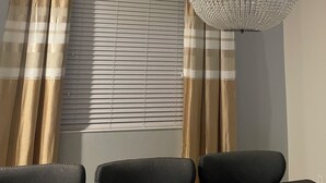 Habitació amb un candelabrum, cortines i una finestra amb persianes.