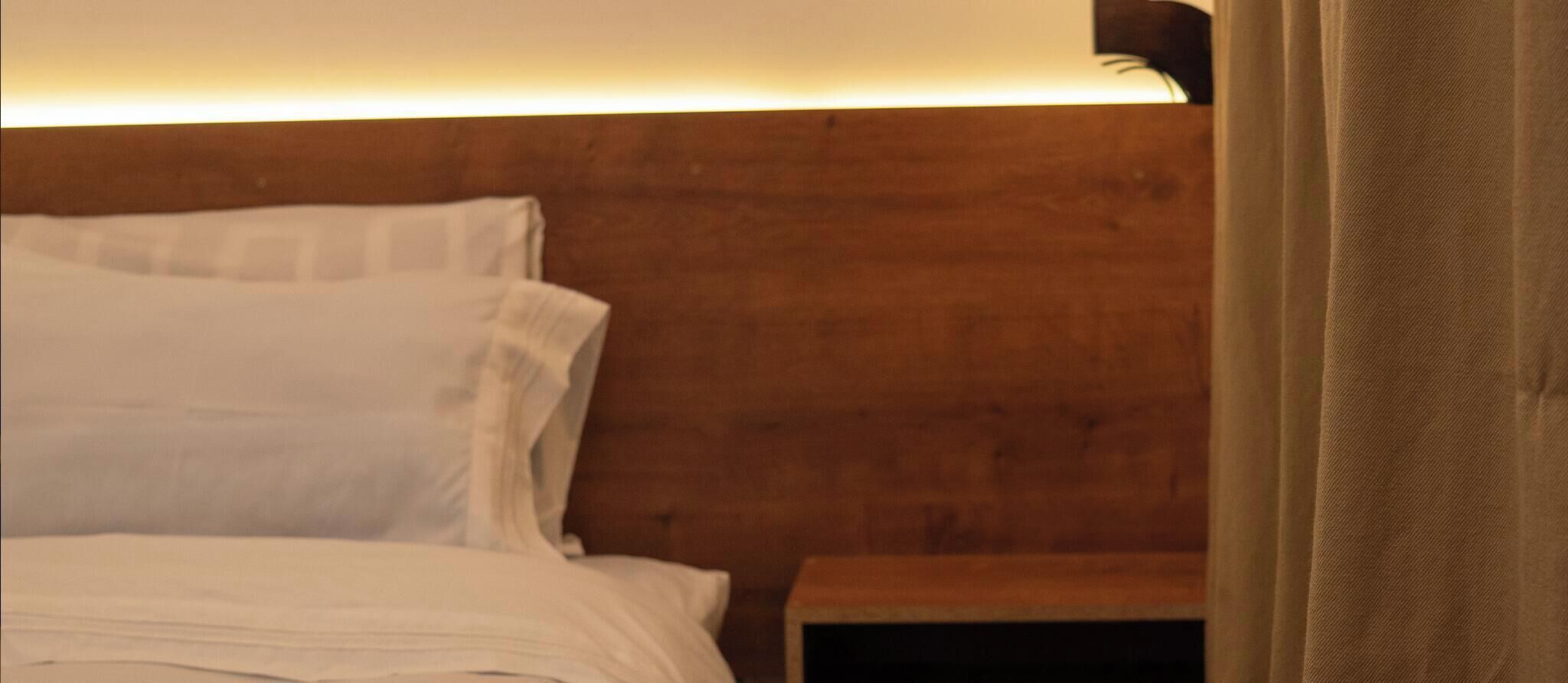 A bed with white bedding and a wooden headboard.