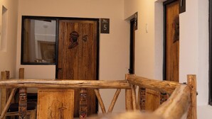 A hallway with wooden doors numbered 5 and 6, a rustic wooden railing, and a large window on the right. - Hostal KoryWasy (Uyuni)