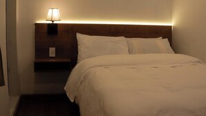 A hotel room with a neatly made bed, a bedside lamp, and a nightstand. - Hostal KoryWasy (Uyuni)