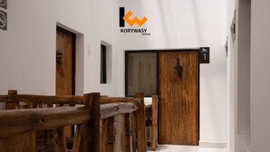 A hallway with wooden furniture, a sign for room 1, and a logo for Korywasy Hostel. - Hostal KoryWasy (Uyuni)