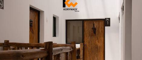 Un pasillo con muebles de madera, un cartel que indica la habitación 1 y el logotipo de Korywasy Hostel.