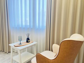 Una habitación moderna con una mesa blanca, una silla y un ventanal con cortinas de gasa.