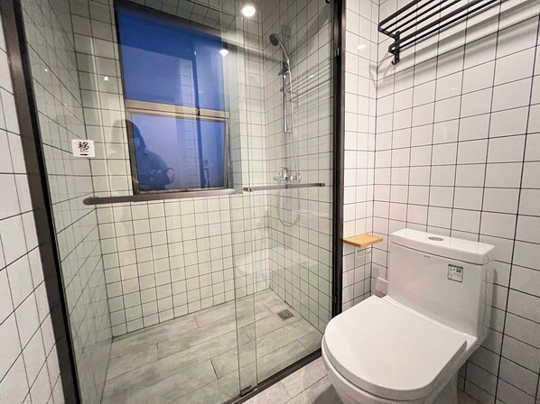 A bathroom with a glass-enclosed shower, a toilet, and a small shelf. - YUEXI (Shanghai)