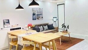 A modern dining area with a wooden table and chairs, a sofa, and a floor lamp.