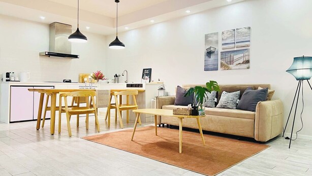 A modern living room with a sofa, coffee table, and dining area.