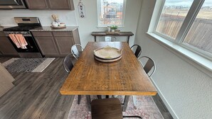 Un coin repas avec une table en bois, des chaises, un tapis et une vue par la fenêtre.