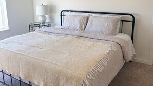 Une chambre à coucher bien aménagée, avec un lit, une table de chevet dotée d’une lampe et des panneaux décoratifs sur les murs.