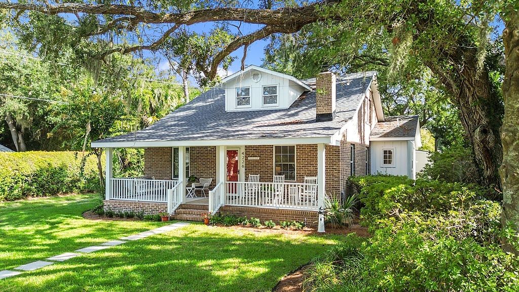 A single-story house with a porch, brick exterior, and a small attached garage.