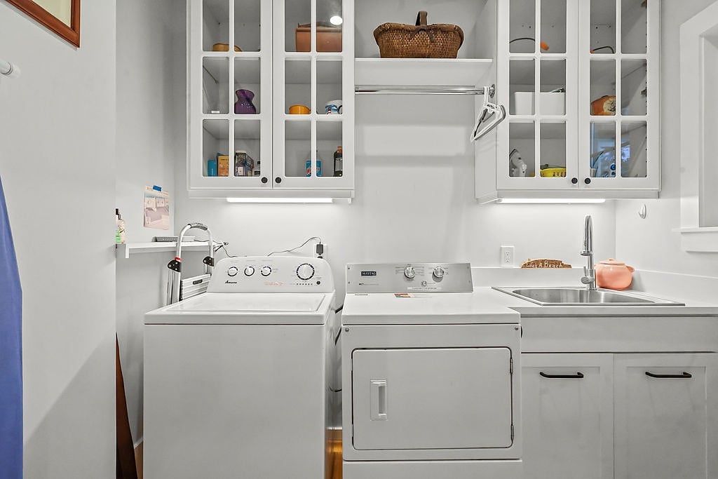 Une buanderie équipée d’un lave-linge, d’un sèche-linge et de placards situés au-dessus.
