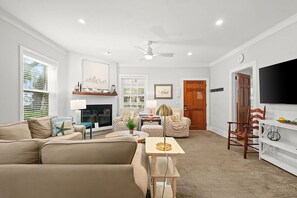 A living room with a sofa, a coffee table, a fireplace, and a television. - Dog Friendly, 5-bedroom Home on East Beach, 100 Yards to Beach Access, Perfect for Family Getaways! (Saint Simons Island)