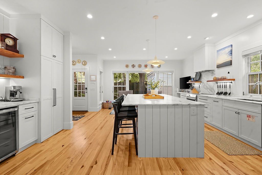 Une cuisine moderne avec des meubles blancs, un îlot central et un coin repas avec des chaises.
