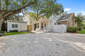 A two-story house with a gravel driveway and a white fence. - Dog Friendly, 5-bedroom Home on East Beach, 100 Yards to Beach Access, Perfect for Family Getaways! (Saint Simons Island)