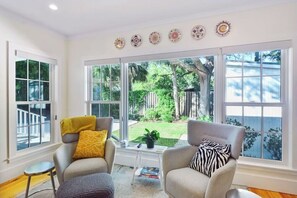 A room with two armchairs, a small side table, and a large window with a view of a backyard. - Dog Friendly, 5-bedroom Home on East Beach, 100 Yards to Beach Access, Perfect for Family Getaways! (Saint Simons Island)
