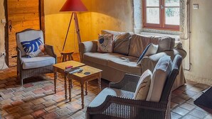 A cozy living room with a wooden door, a red floor lamp, a sofa, a chair, and a small table. - Le Moulin Mathy - SAINT PIERRE LE VIEUX (SAINT PIERRE LE VIEUX)