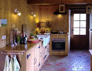A wooden interior with a kitchen area, including a stove, sink, and various kitchen items. - Le Moulin Mathy - SAINT PIERRE LE VIEUX (SAINT PIERRE LE VIEUX)