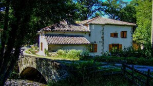 A two-story stone house with a tiled roof, a stone bridge, and a wooden fence. - Le Moulin Mathy - SAINT PIERRE LE VIEUX (SAINT PIERRE LE VIEUX)