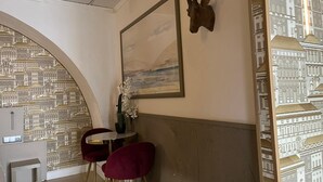 A room with a cityscape wallpaper, a framed painting, a vase with flowers, and a wooden headboard. - ✨ Independent Stay: King Bed, Private Bathroom and Netflix (Faro)