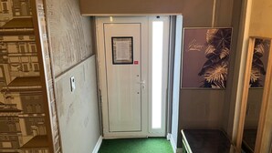 A narrow hallway with a green carpet, a white door with a notice, and a framed artwork on the wall. - ✨ Independent Stay: King Bed, Private Bathroom and Netflix (Faro)