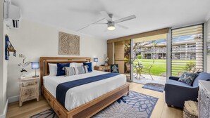 Une chambre moderne avec un grand lit, un ventilateur de plafond et une vue sur la terrasse extérieure.