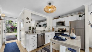 Une cuisine moderne avec des armoires blanches, des appareils en acier inoxydable et un tapis bleu.