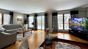 A modern living room with a grey sofa, a coffee table, and a TV on a stand. - Charming Lakeview Cottage | Algonquin Shores (Dwight)